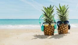 beach-background-with-cool-pineapples-wearing-headphones_23-2147836098